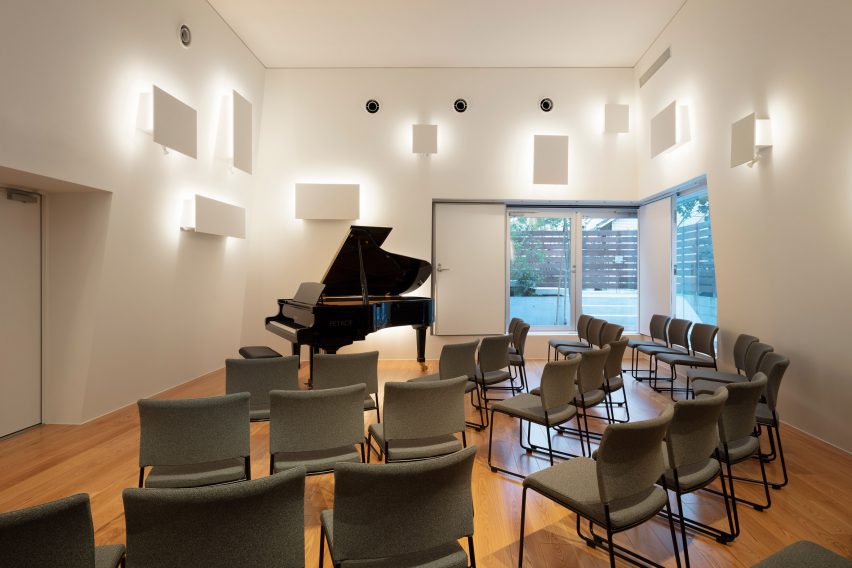 Small auditorium with grand piano and backlit wall panels 