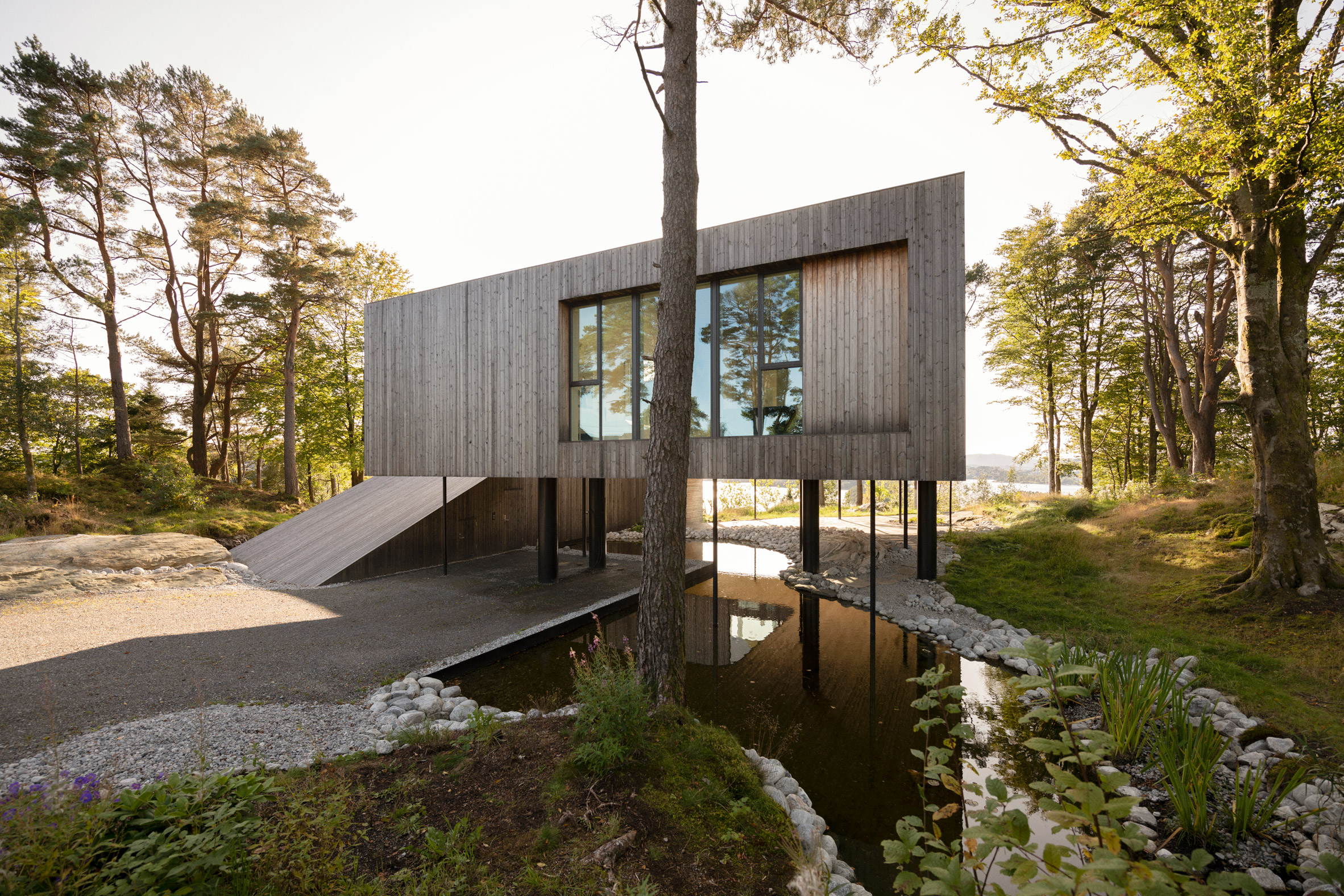 Two-storey timber villa raised on stilts over water in Norway