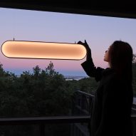 Woman turning on Sunne solar energy lamp by Marjan van Aubel in front of a window