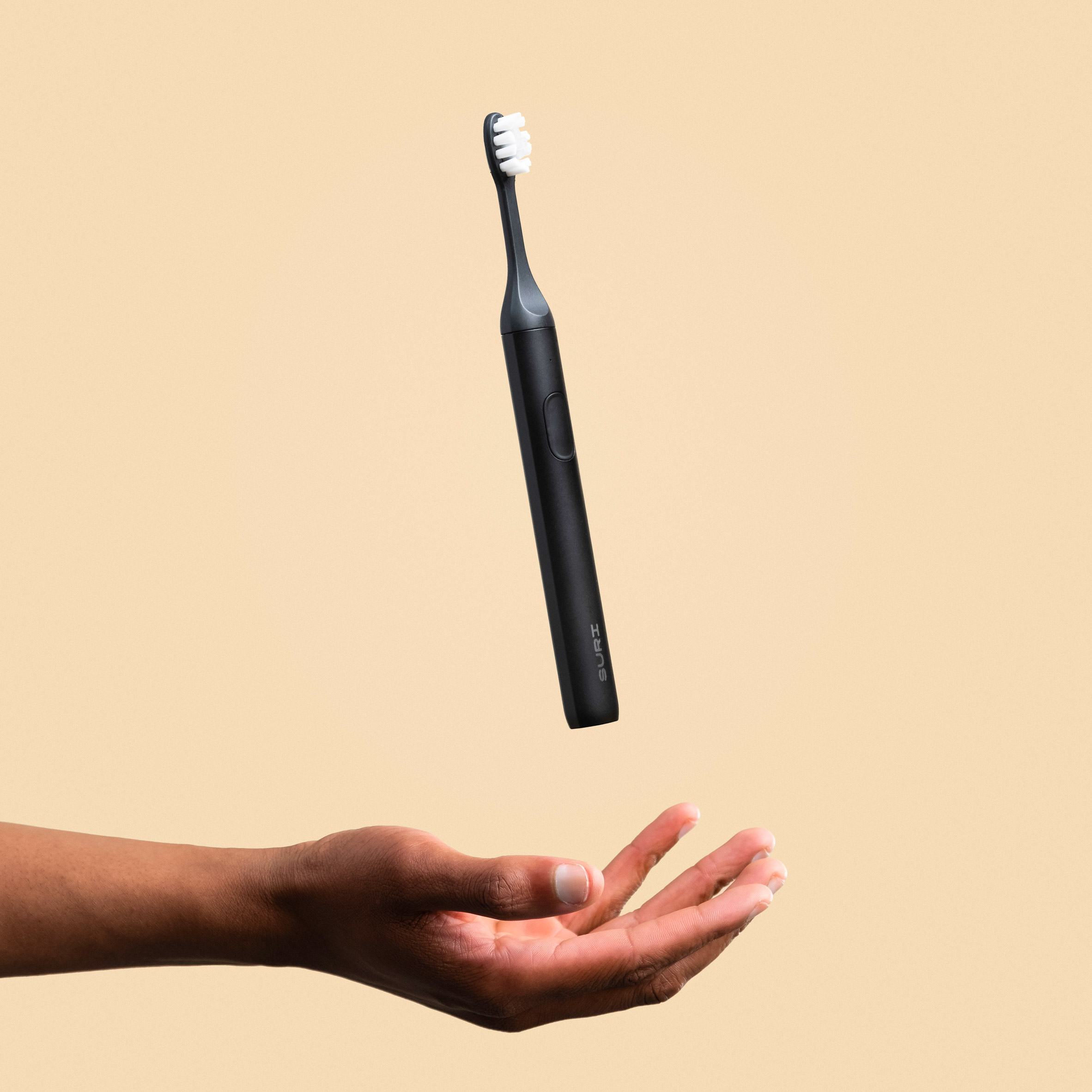 A hand throwing a black electric toothbrush in the air