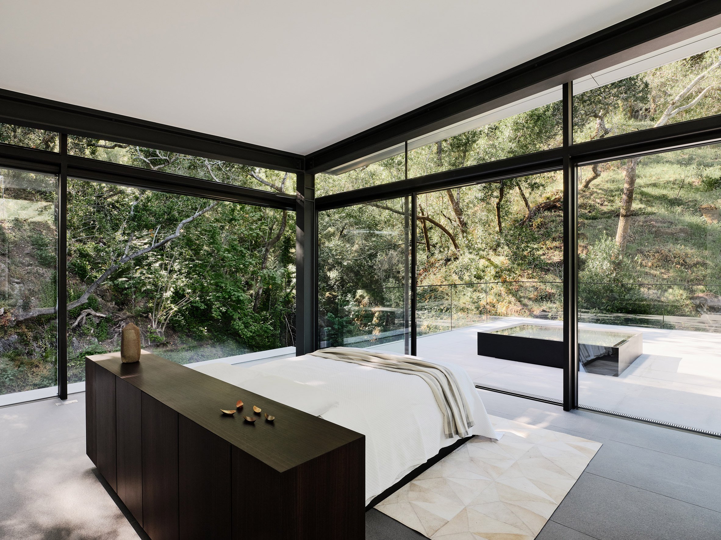 Bedroom in forested creek with panoramic views of surroundings through glass walls