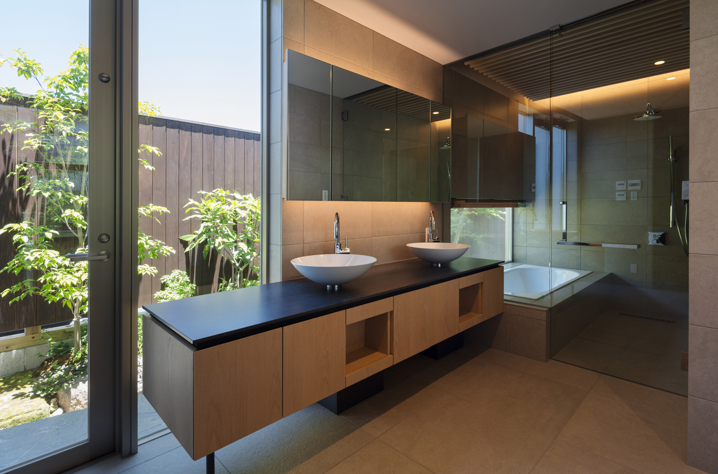 Bathroom with glass door behind cabinet and back-lit mirror