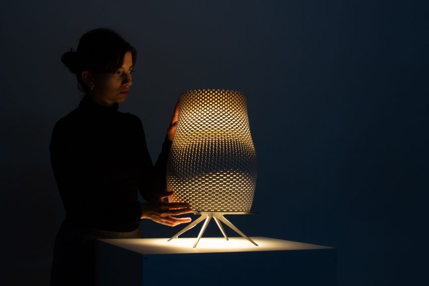 Person touching a lit lamp in a dark room