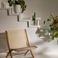 Photograph showing rattan and wooden chair by white steps with plants