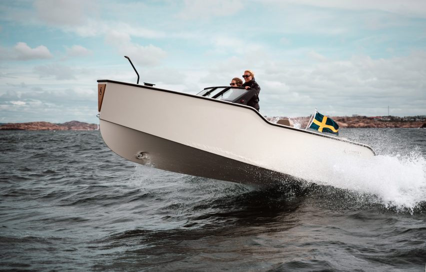 Small white electric boat glides over a wave in the sea at full speed
