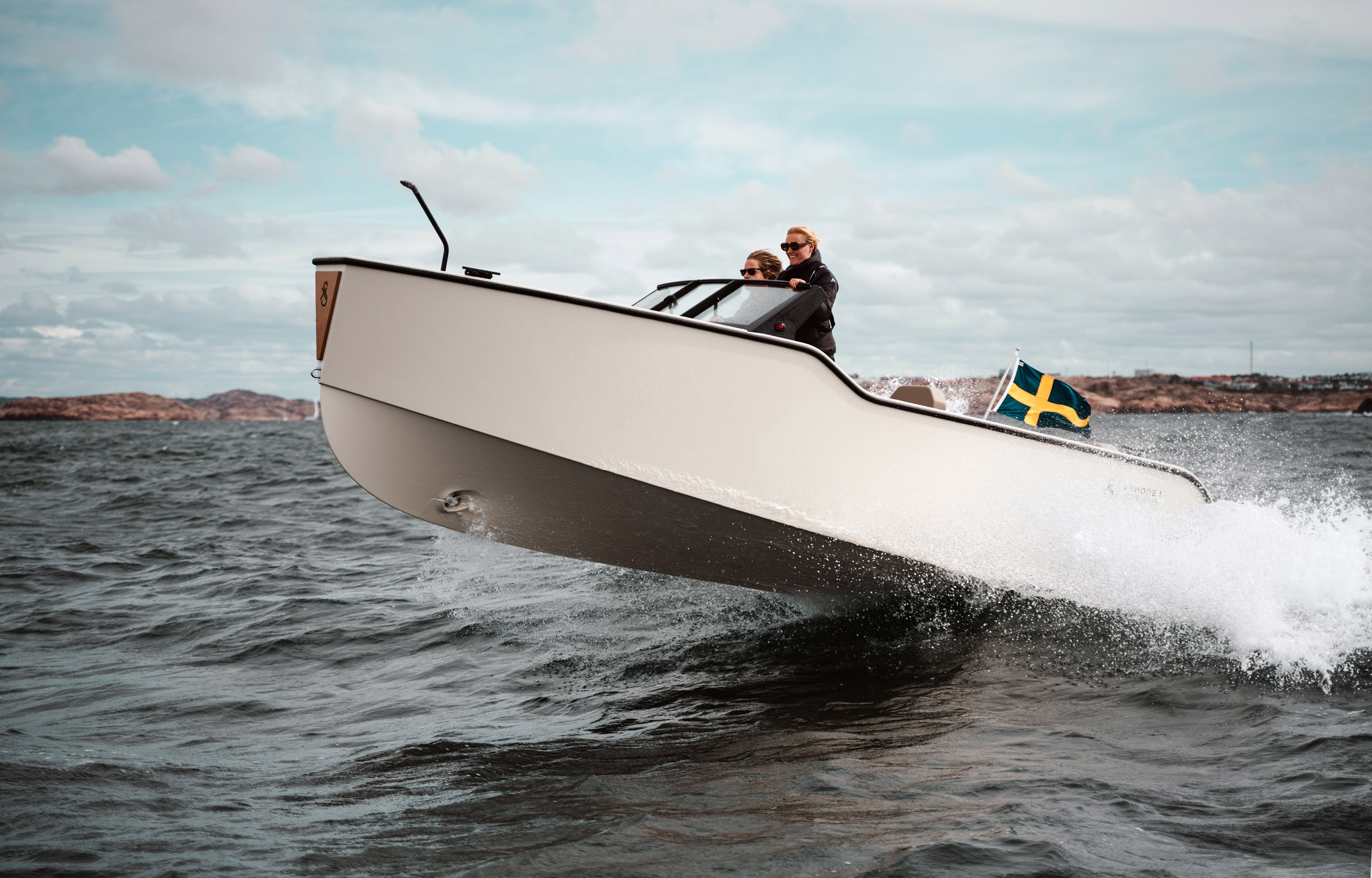 Small white electric boat glides at full speed over a wave in the sea