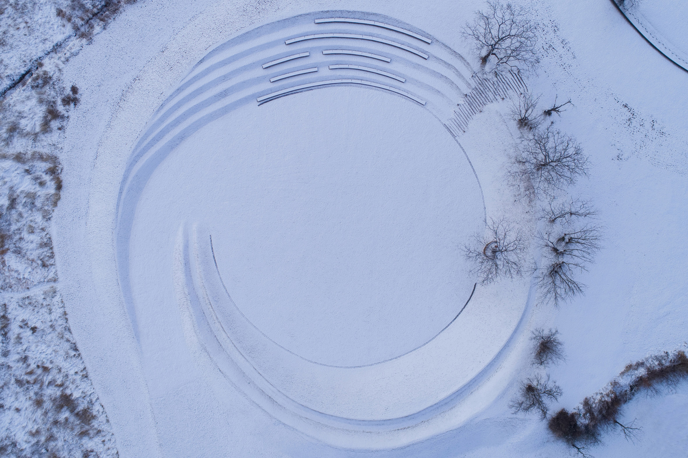 Aerial view of amphitheatre by Z'scape with curved benches covered with snow