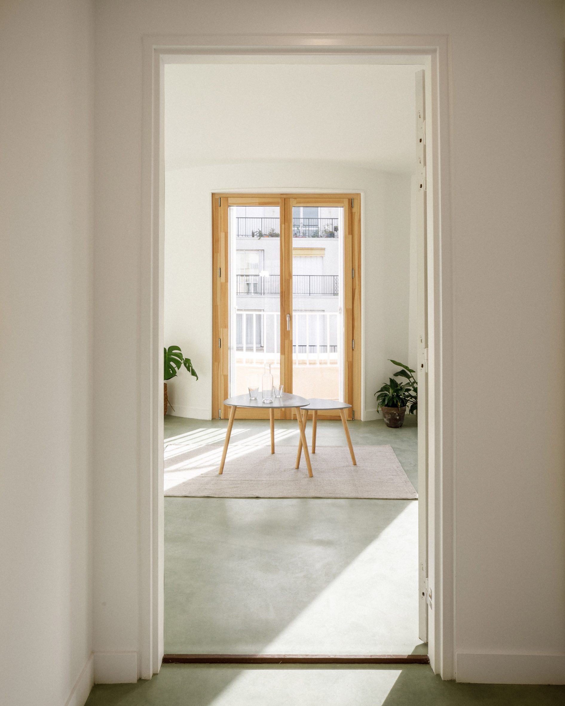 Interior of the 12 Rue Jean-Bart housing project showing white walls, timber door frames and a view from the entrance through the living room and the street-facing window