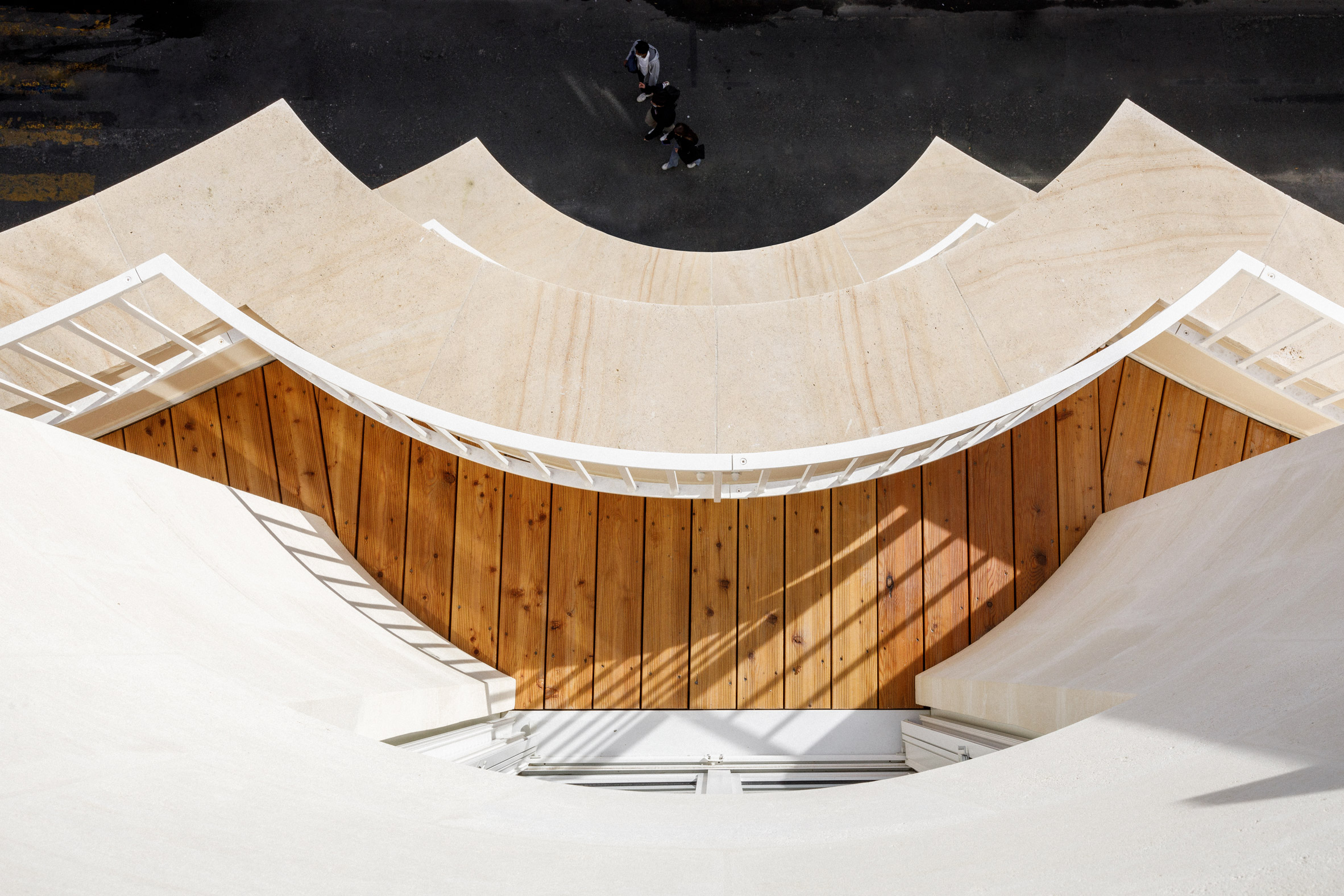 Wood-decked curved terraces built into a curved limestone facade