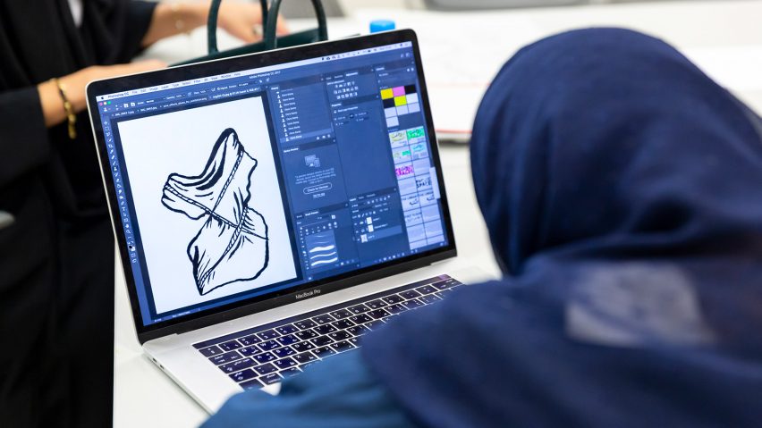 Photograph showing laptop screen with student designing using software