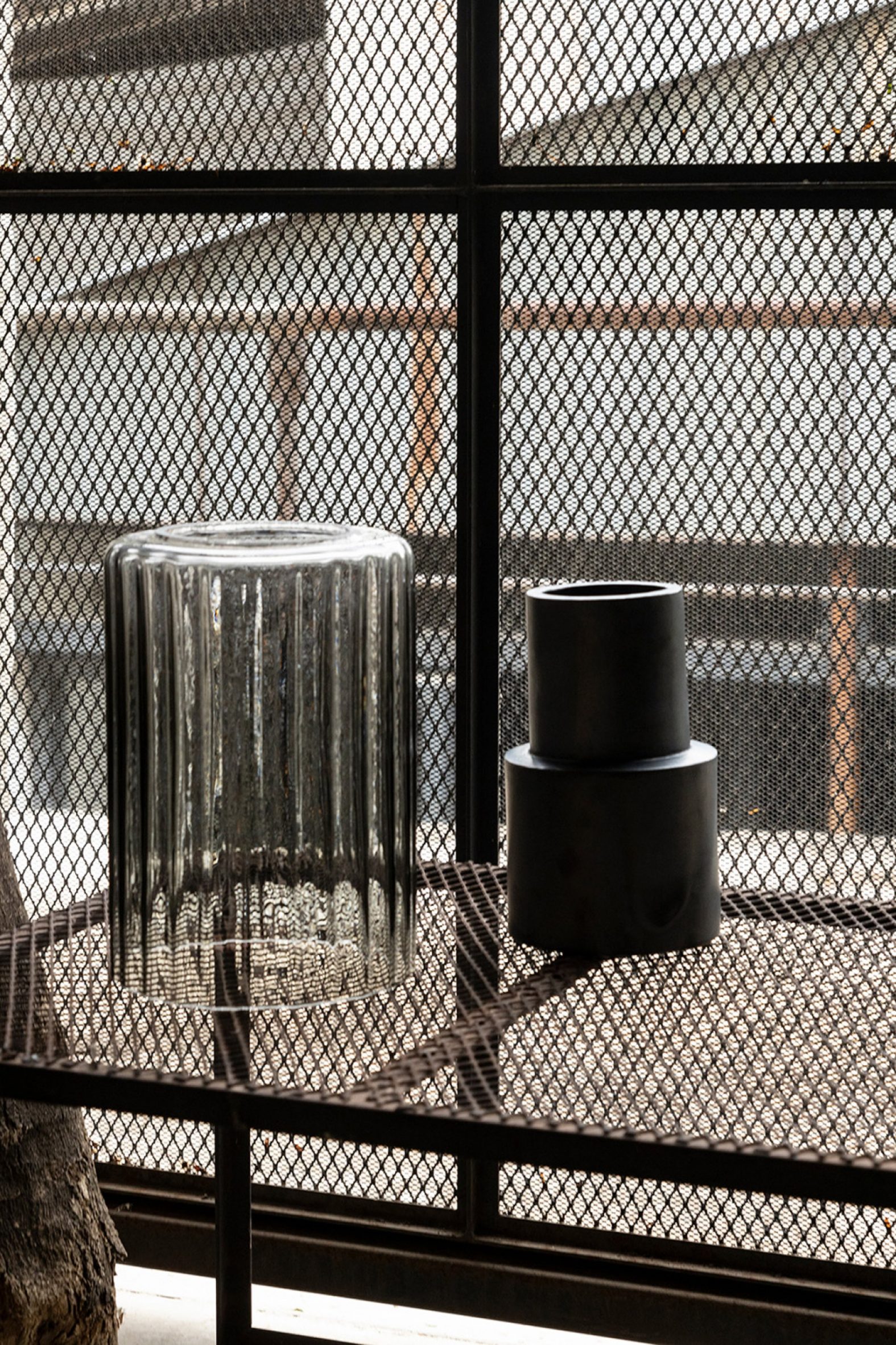 Rippled glass lampshade next to a black ceramic cylinder