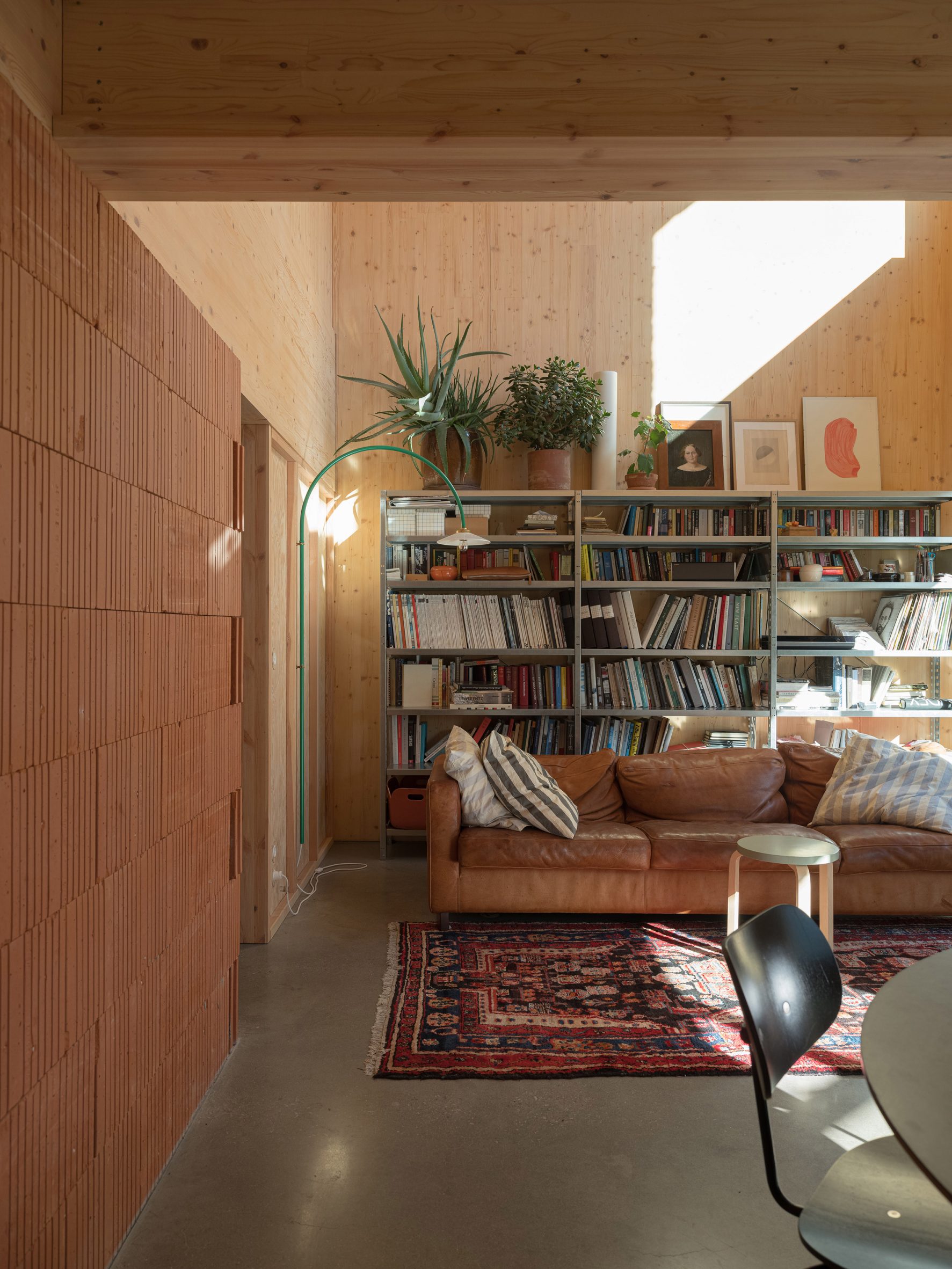 Interior image of a wood-lined living area with a sofa and book case at Twelve Houses