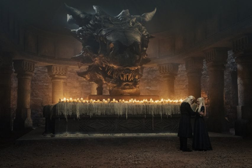 A large dragon skull above an altar with lots of candles