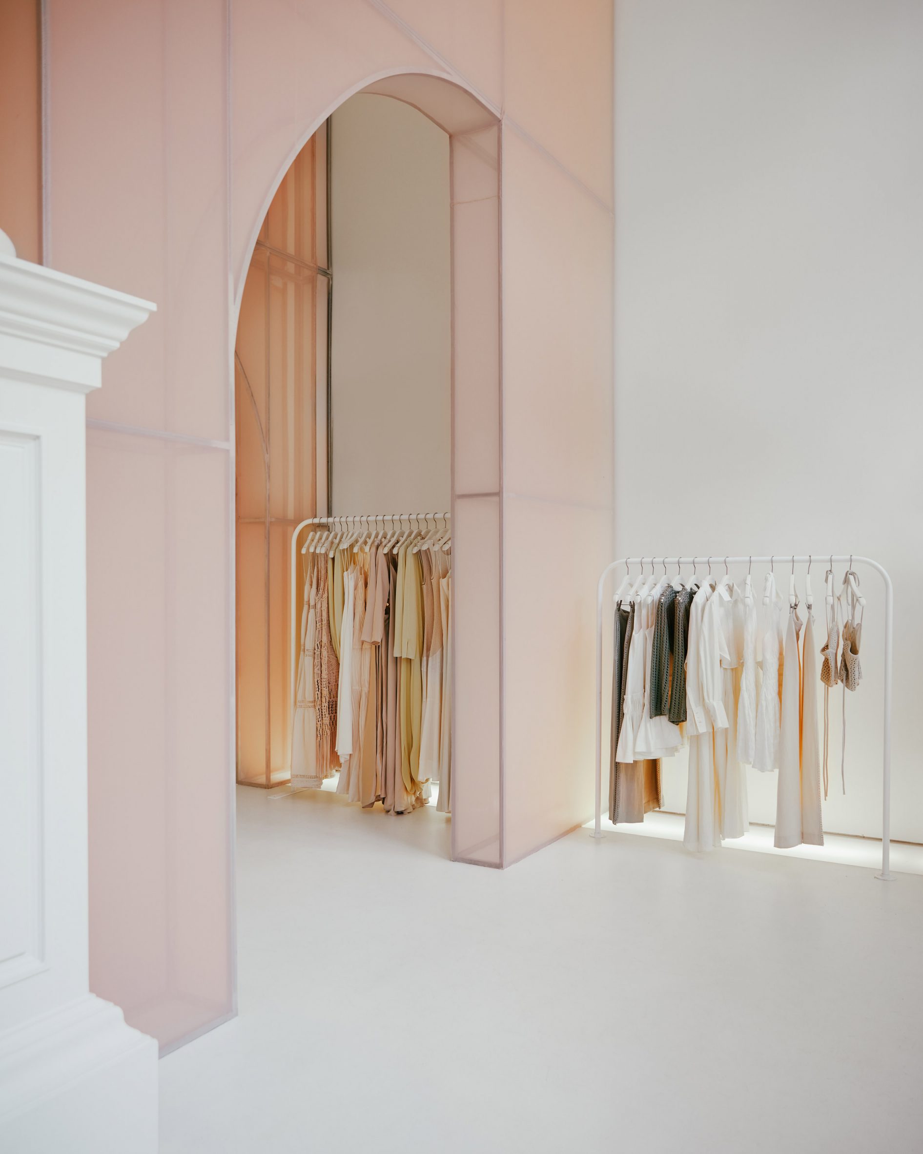 Clothing displayed on white rails between fabric partitions