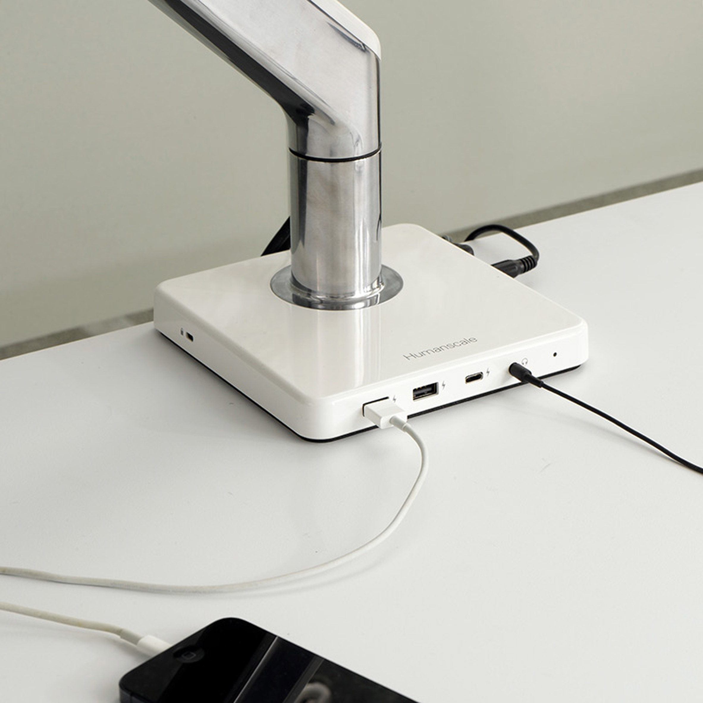 White device on white table with phone charging while connected to it
