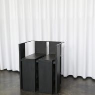 Photograph of black chair in front of white curtain