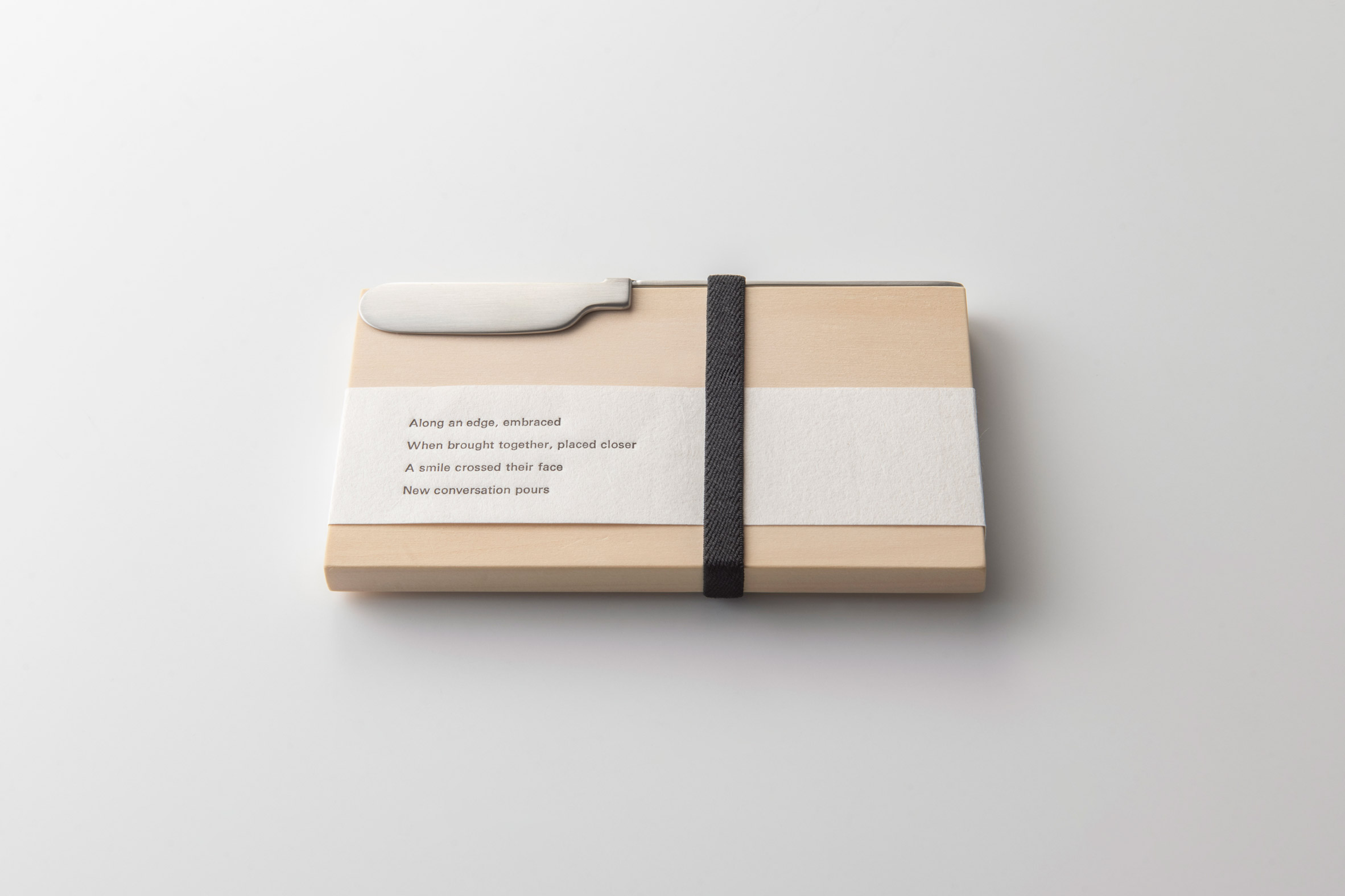 Oku knife packaged with a wood chopping board and poem printed on paper wrap
