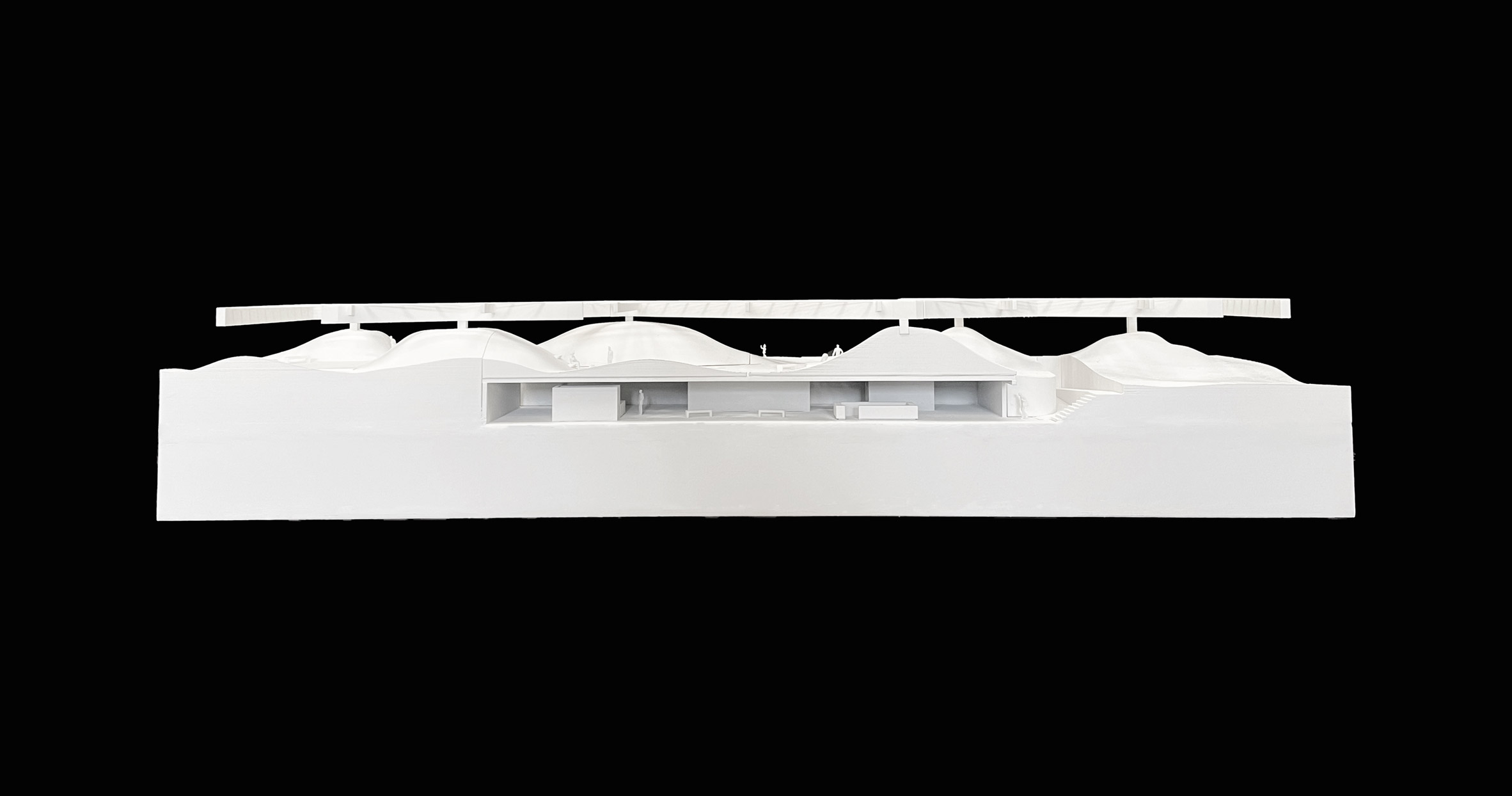 A photograph of a white architectural model against a black background.