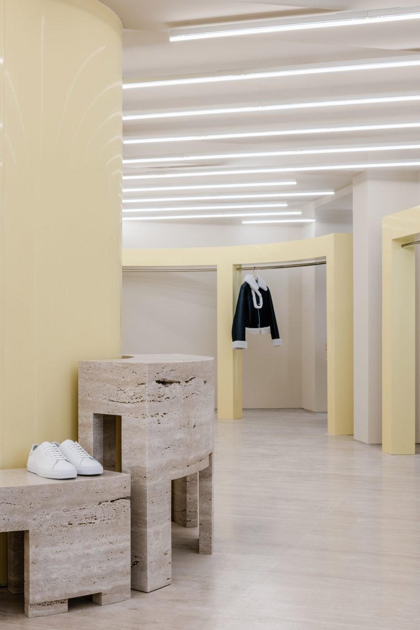 Plinths and butter yellow clothing rails in store interior by Halleroed.