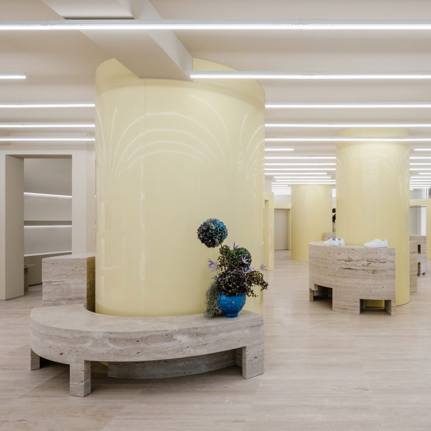 Glossy butter yellow columns and travertine plinths in Axel Arigato's Berlin store