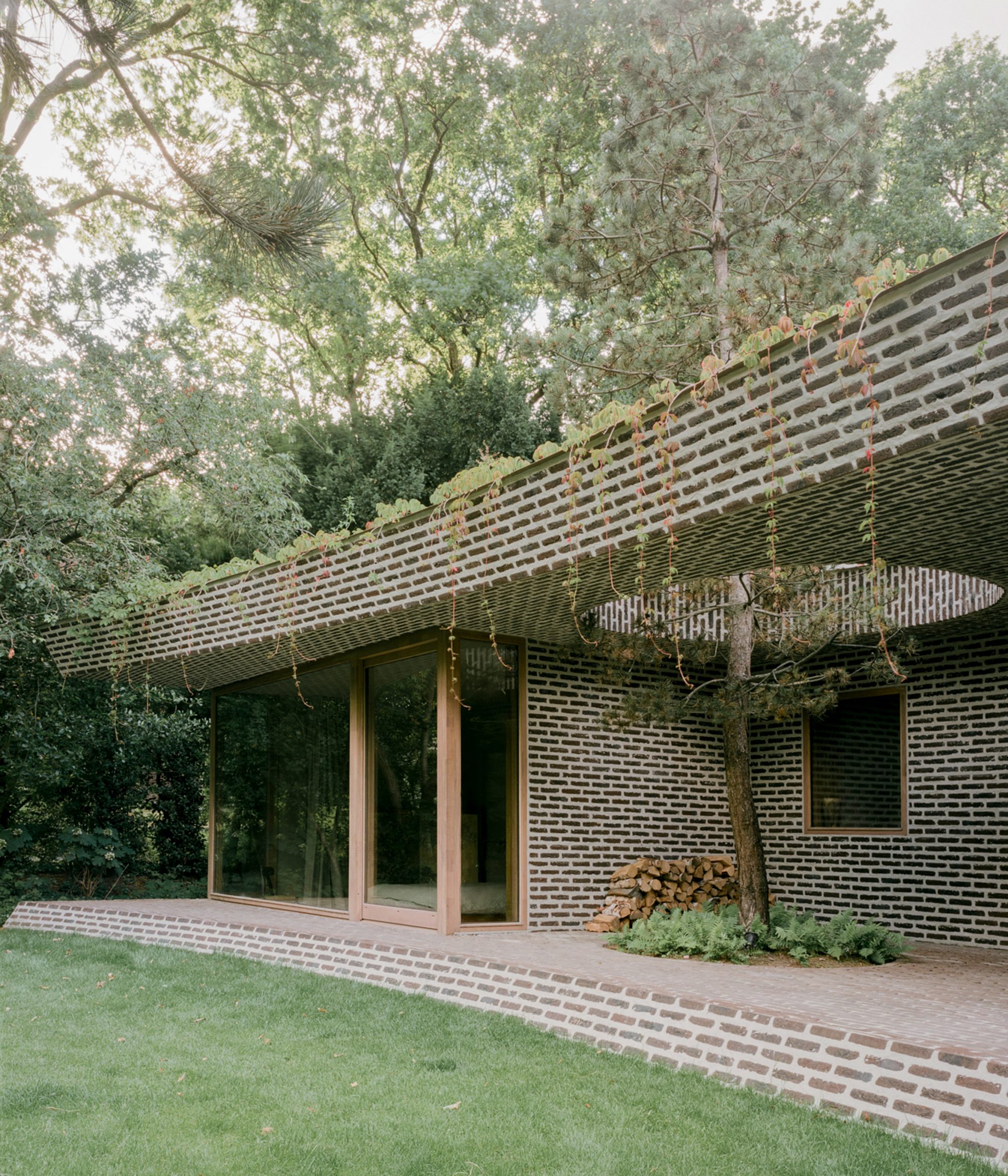 Exterior image of a curving brick pavilion added to the rear of BD House