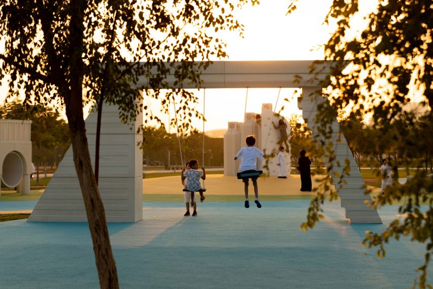Дети играют на качелях на современной игровой площадке в Дохе