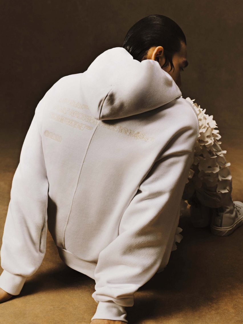 Man in a white Equipment hoodie with appliqué leaves