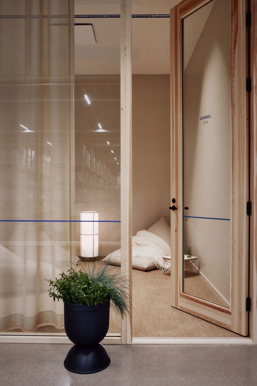 На фото стеклянная офисная дверь с деревянным каркасом и теплым светом, а также бежевая погремушка с ковриком в одном углу.