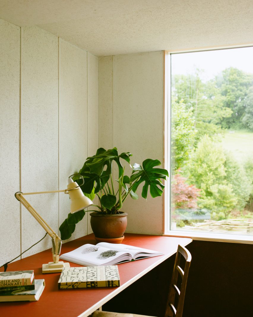 Garden studio with in-built red desk, lamp and plant