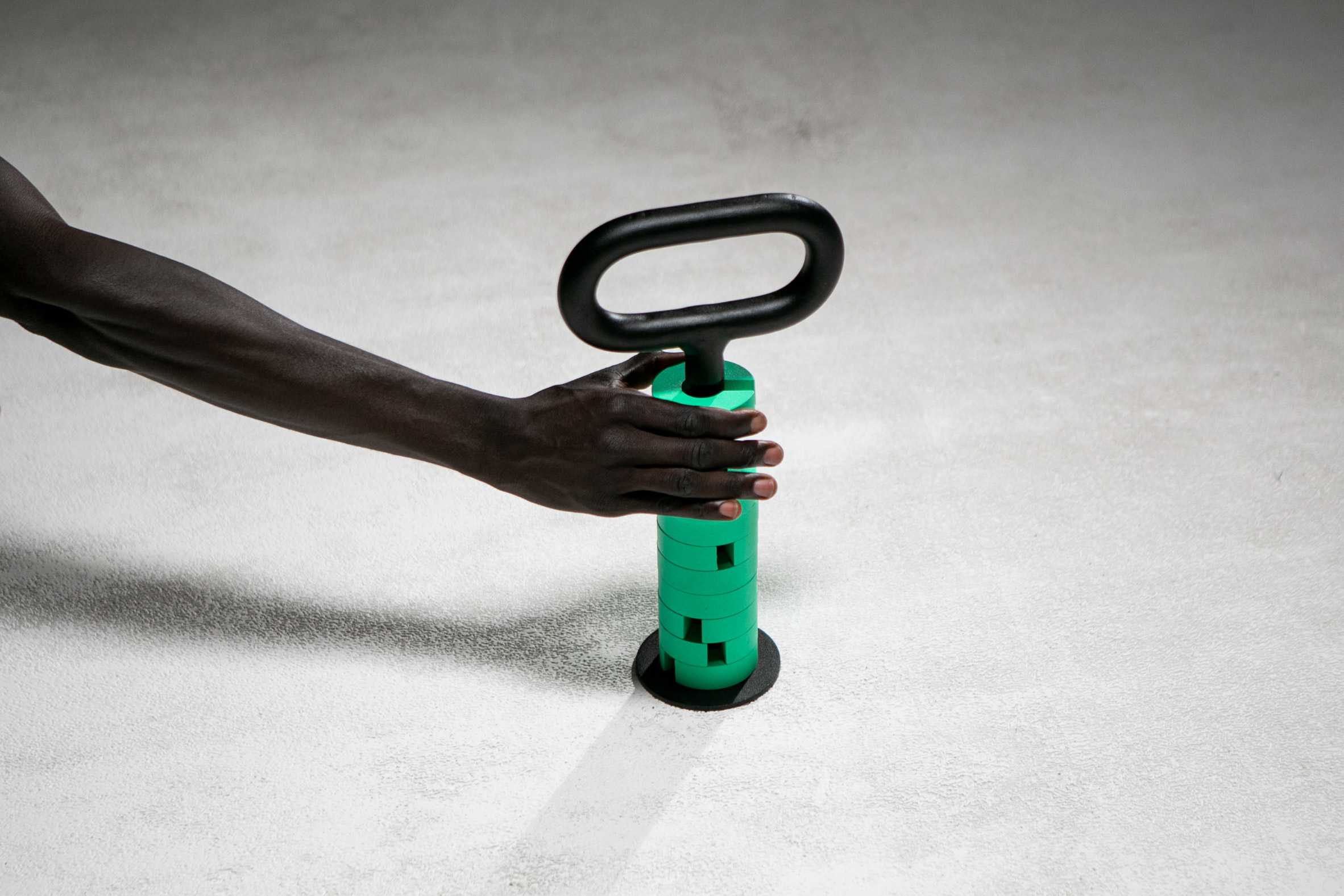 Photo of a hand grabbing Prooff's "Kettlebell" that holds extra green weights on a magazine