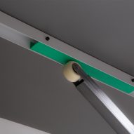 Photo of the underside of the Gas Spring Table showing a skateboard wheel attached to a lever pressing against the tabletop
