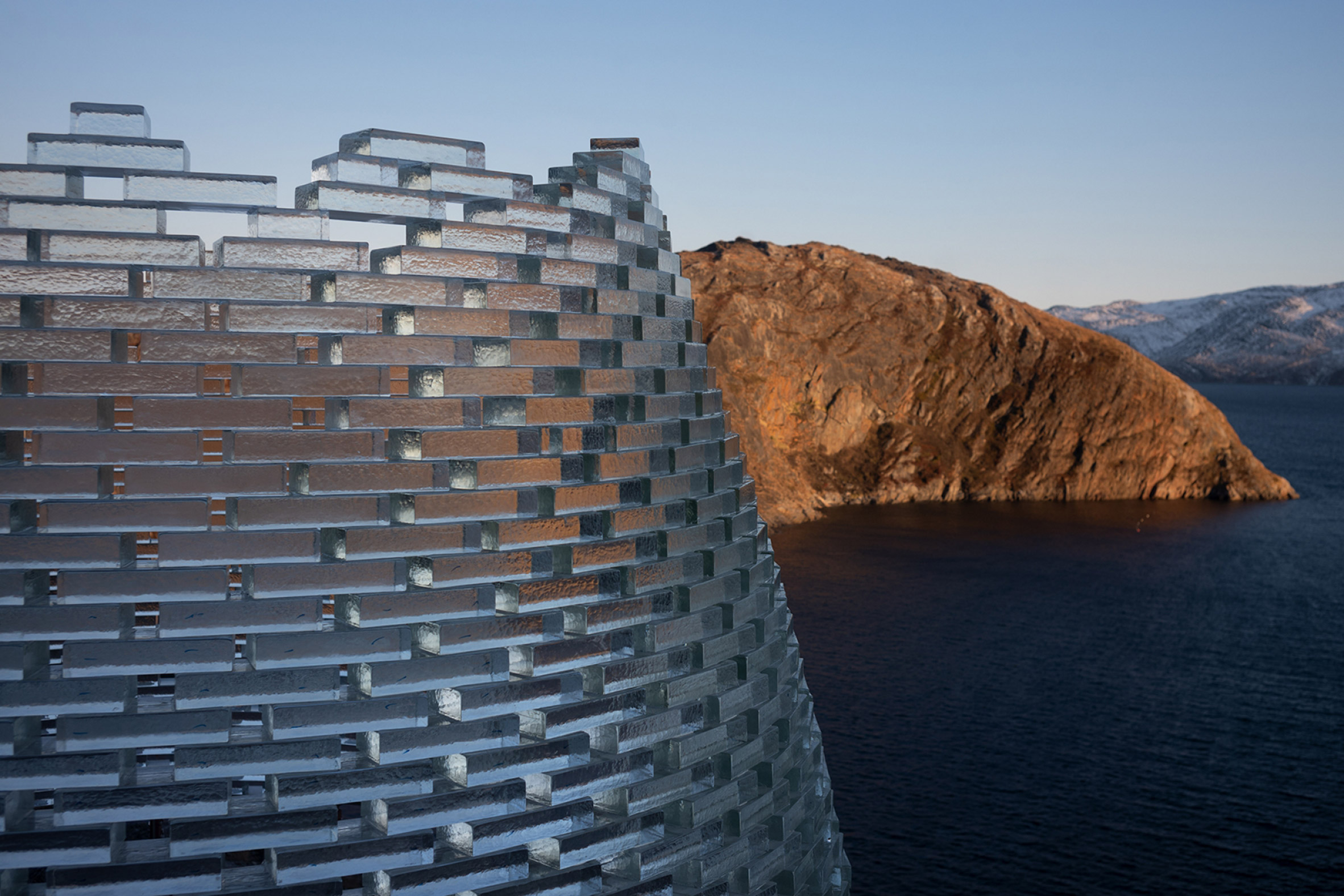 Glass wall pavilion by Konstantin Arkitekter on a rocky hillside overlooking a body of water
