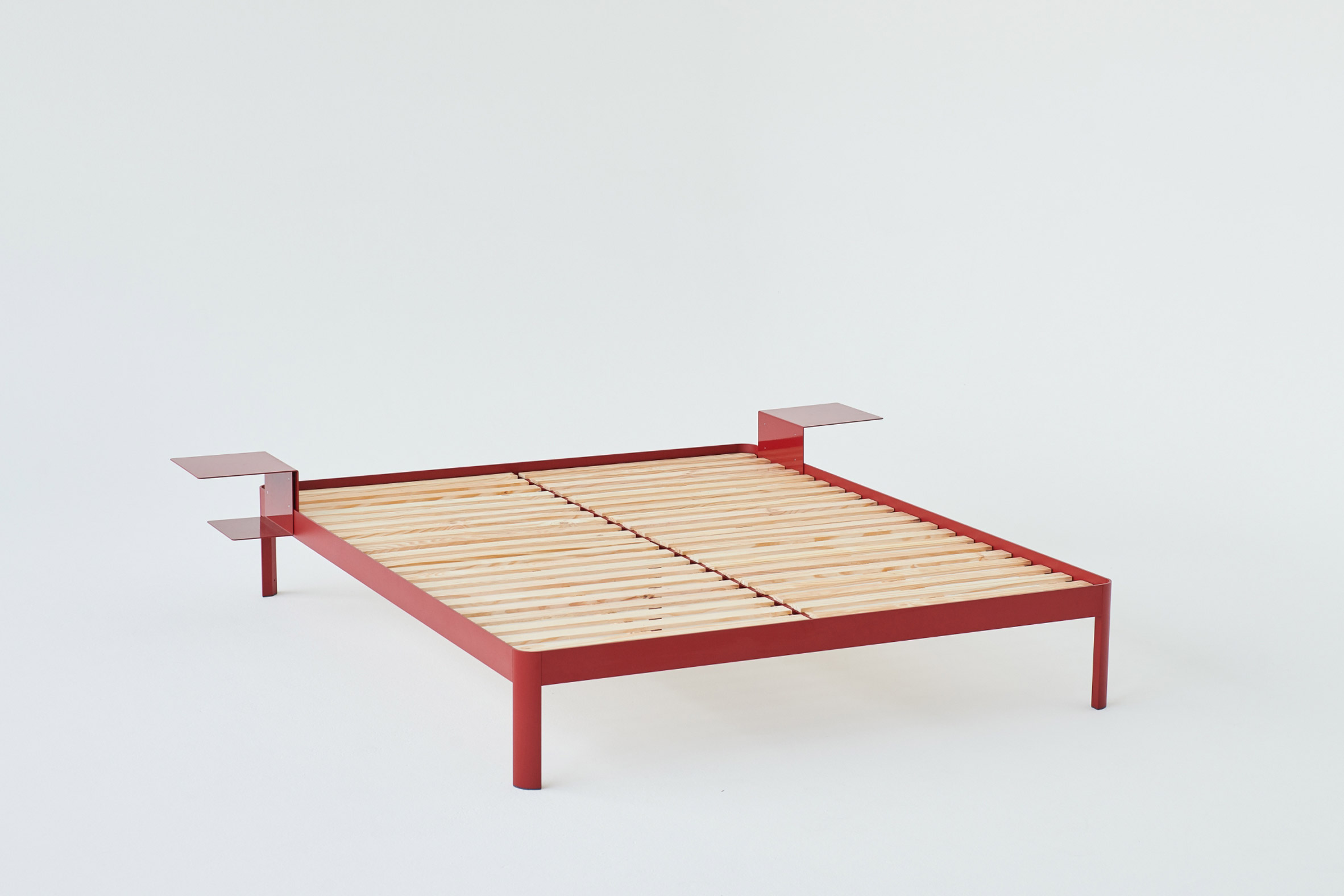 Photograph of a red bed frame with two side tables in a white background
