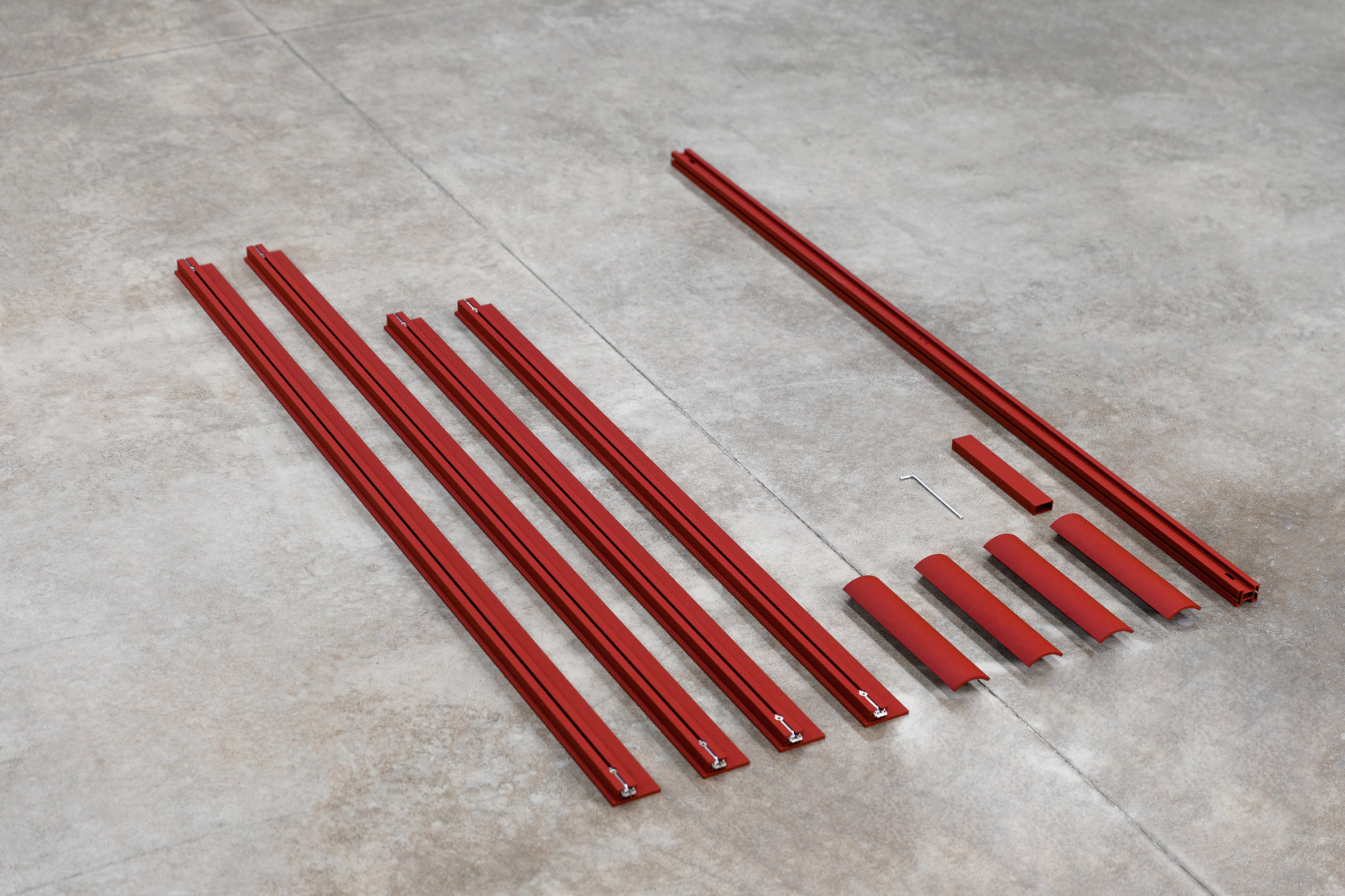 Photograph of ten pieces of red aluminium and a tool