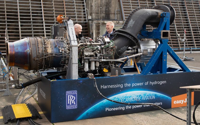 Photo of men standing behind a large engine on a testing site