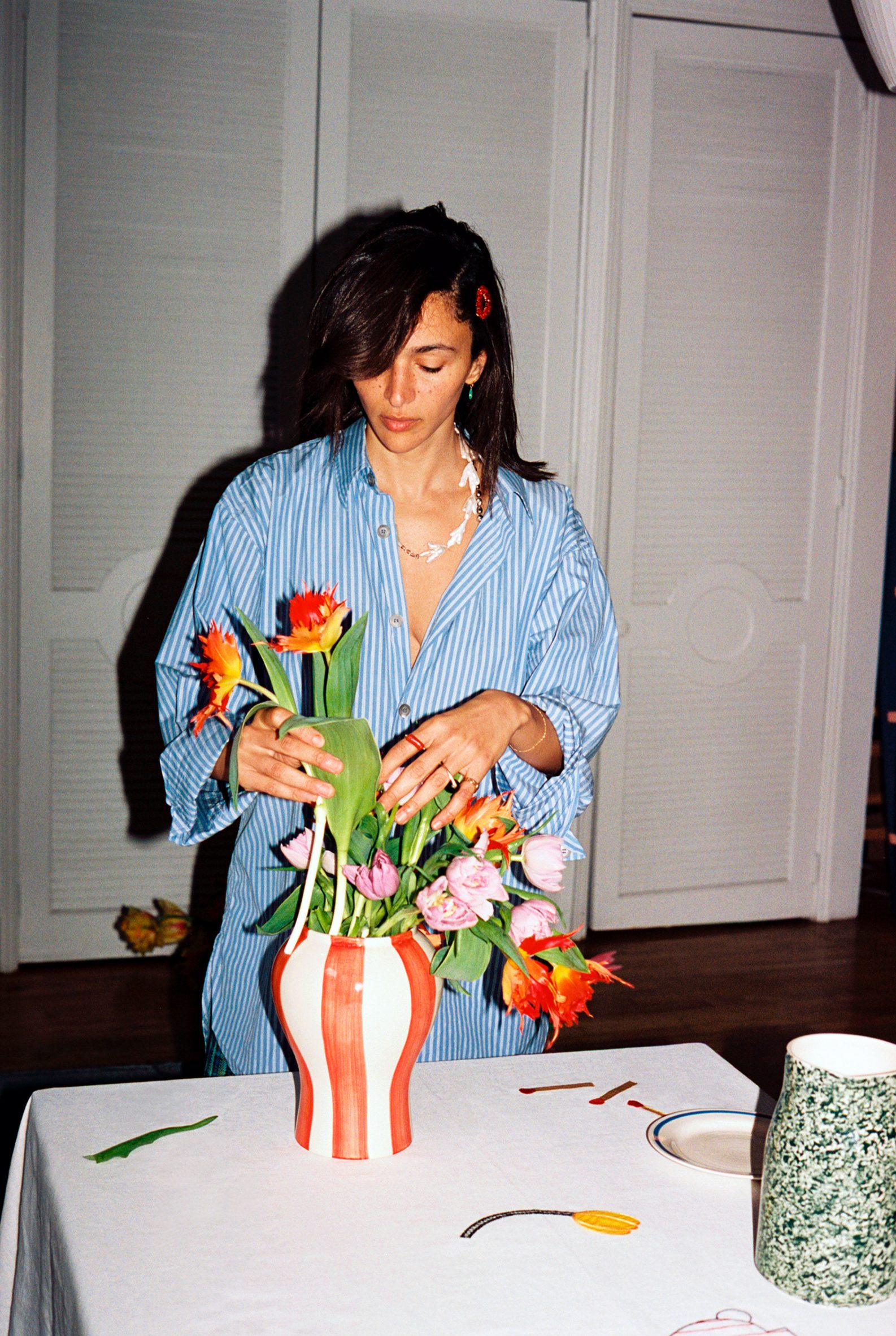 Designer Laila Gohar in a blue-striped shirt arranging flowers