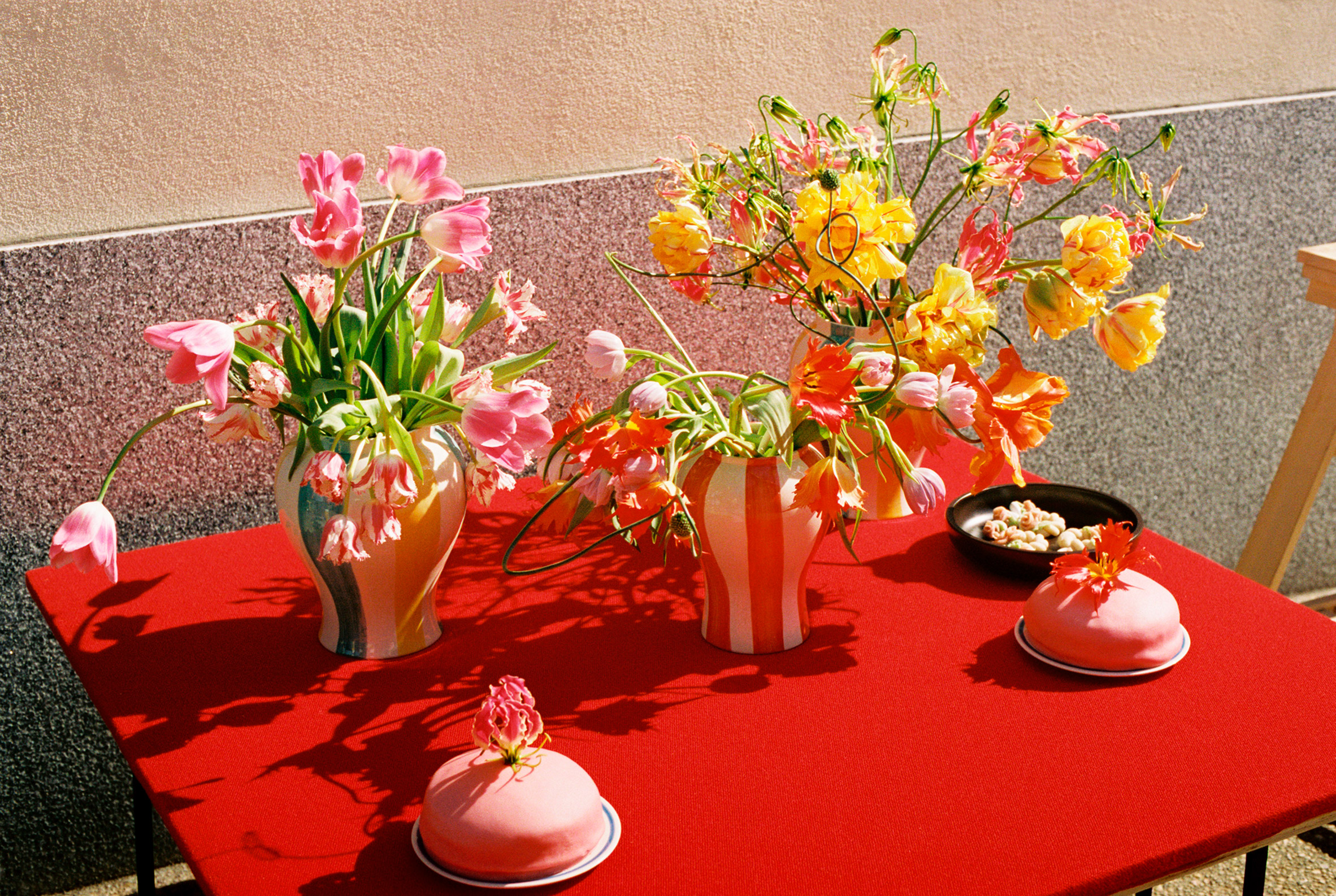 Red table with colourful vases filled with flowers