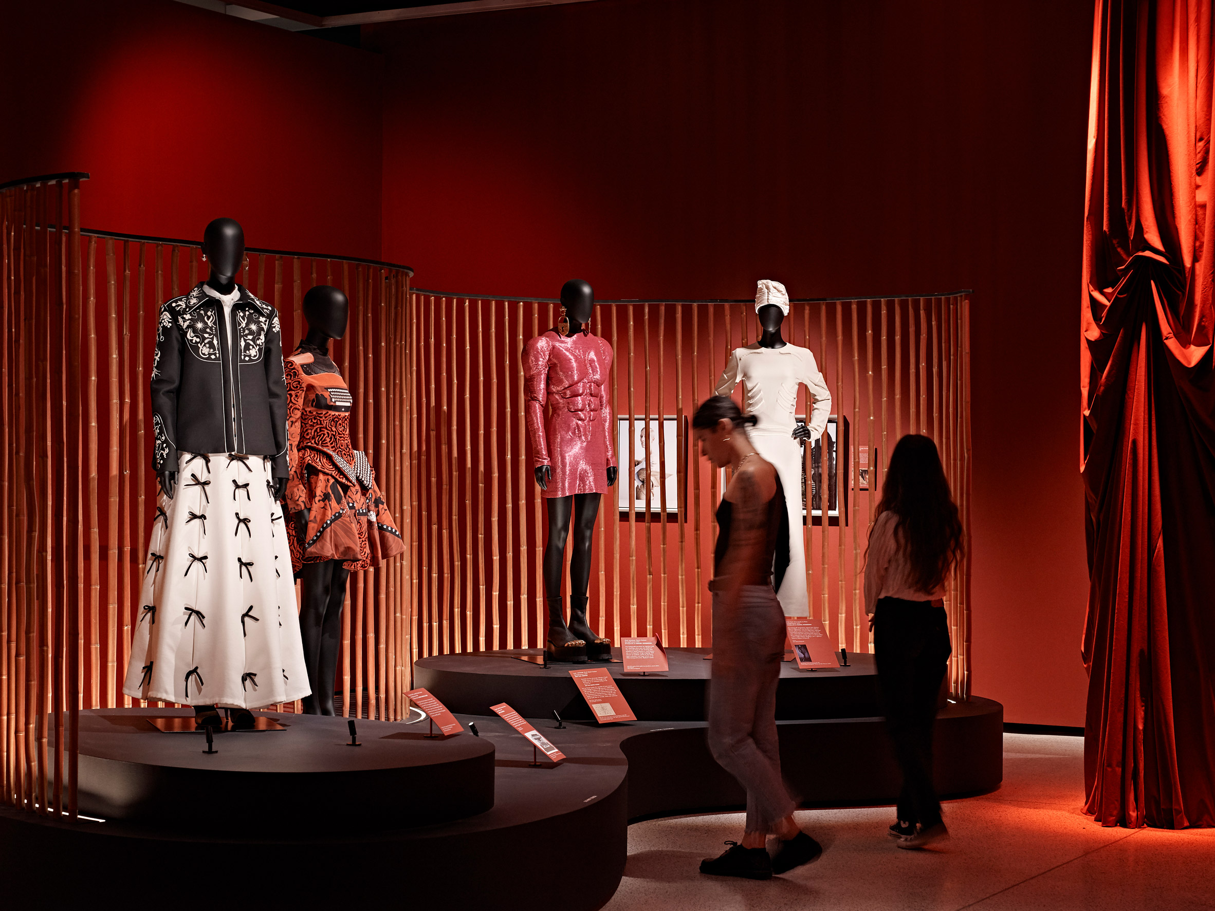 Visitors looking at four mannequins wearing fashion inspired by surrealism