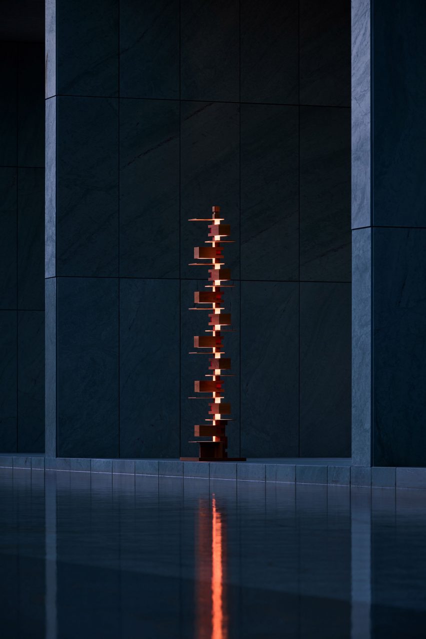 Stacked wooden floor lamp reflected in body of water
