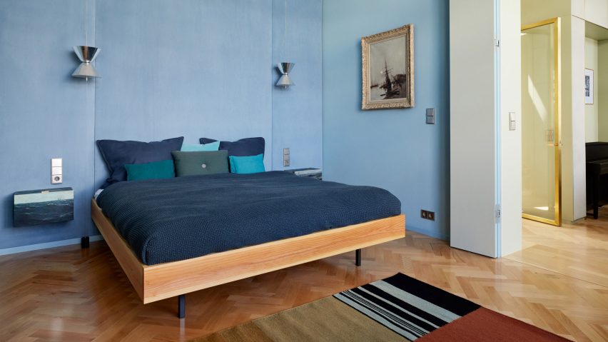 Bedroom of Berlin penthouse by Coordination with blue walls and blue bedspread