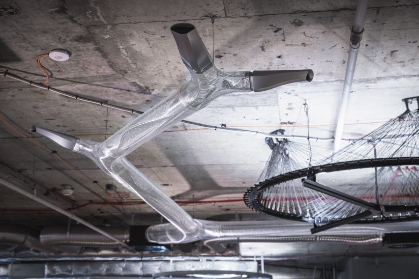 Photo of translucent plastic pipes branching out under a concrete slab ceiling