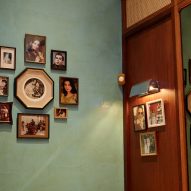 Teal wall with framed photos in Dishoom Canary Wharf