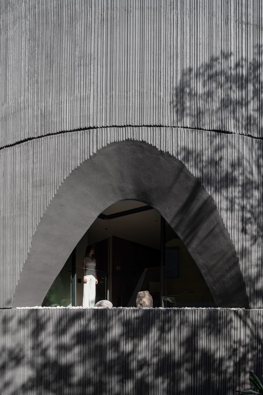Arched window in concrete facade of cylindrical home
