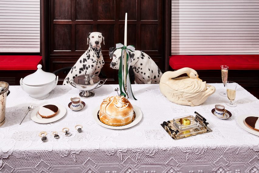 Two dalmatians sit at a table with a meringue on it