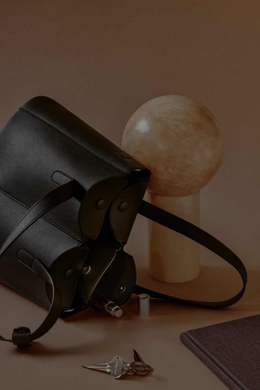 Фотография черной большой сумки на боку с предметами, вываливающимися из карманов