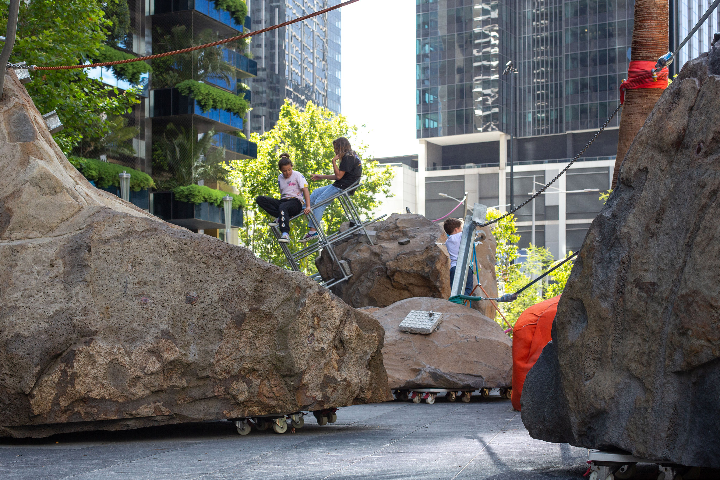 Children play on Mike Hewson's Rocks on Wheels playground sculpture in Melbourne
