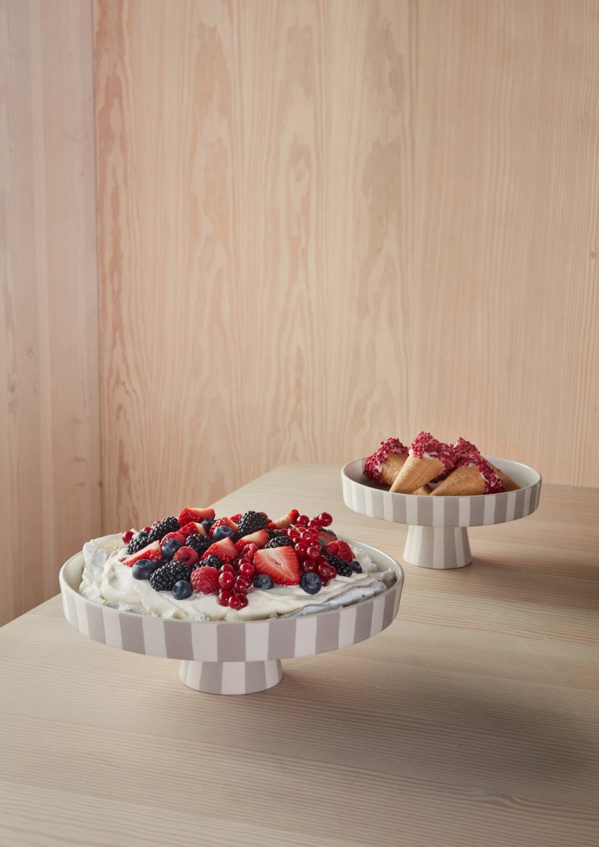 Two bowls on plywood table containing berries and cream
