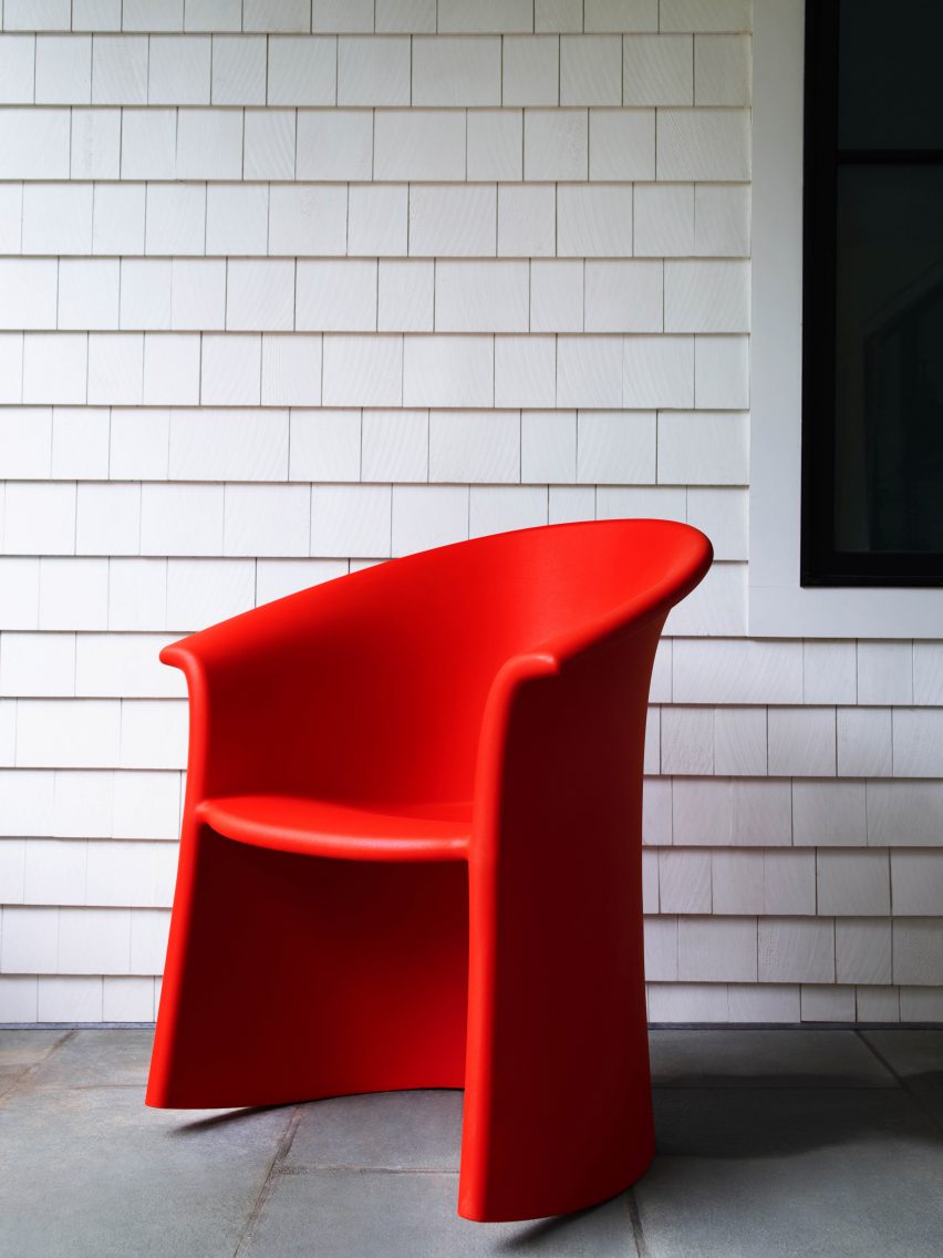Red plastic Vignelli Rocker chair sits against a white tiled wall
