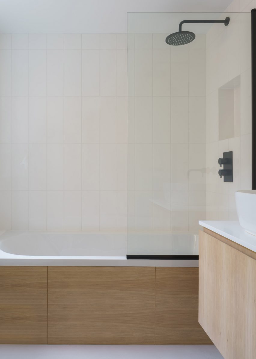 Bathtub with wood cladding surrounded in soft yellow tiles