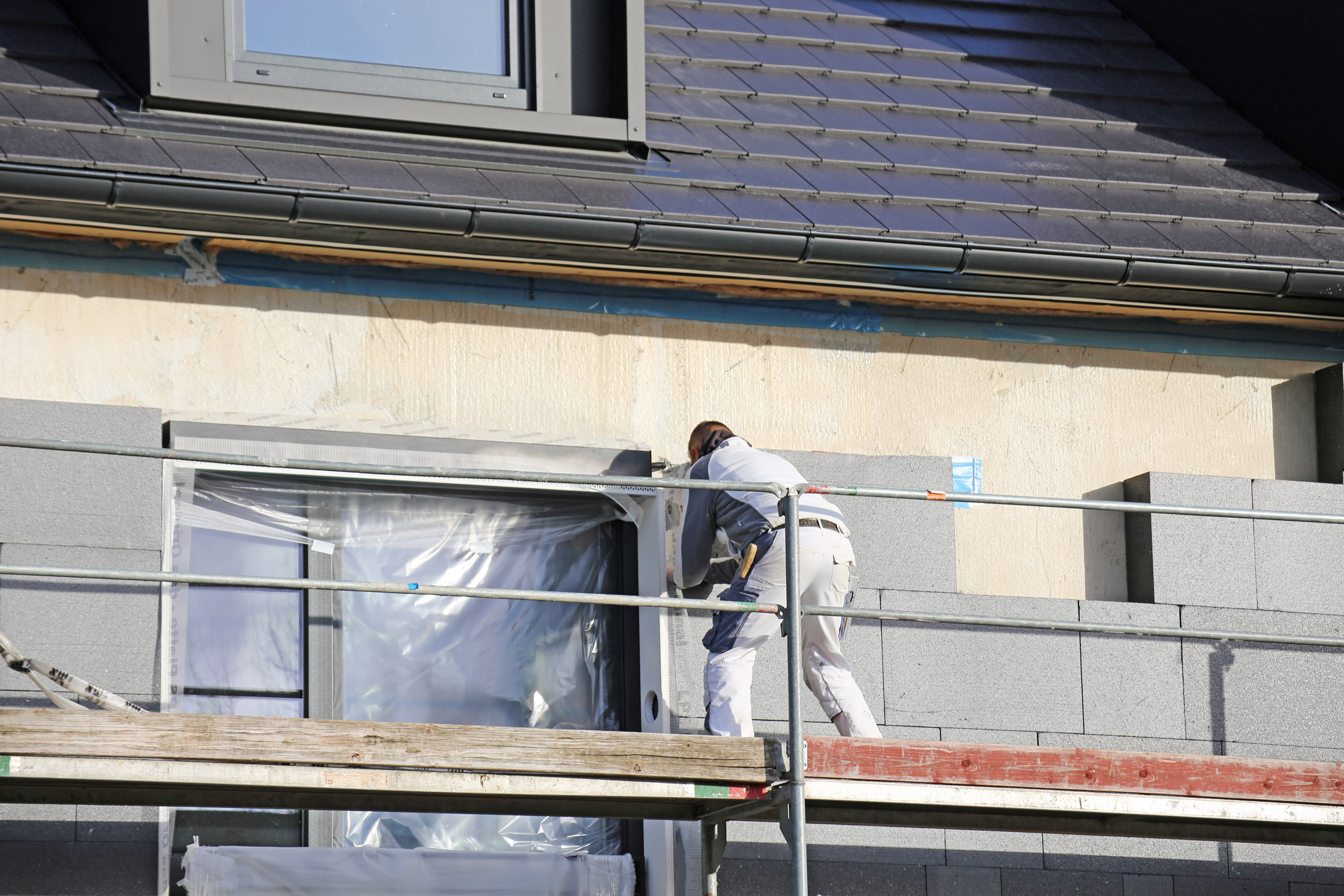 Construction worker applying external insulation to a house